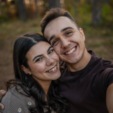 Photo for Man and woman young adult couple in nature take self portrait photo selfie ugc use mobile phone smartphone or make a video call - Royalty Free Image