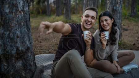 Téléchargez les photos : Jeune couple homme et femme petit ami et petite amie ou mari et femme dans la relation amoureuse tenir tasse de papier de café ou de thé tout en passant du temps ensemble dans la forêt du parc liens amour vraies personnes - en image libre de droit