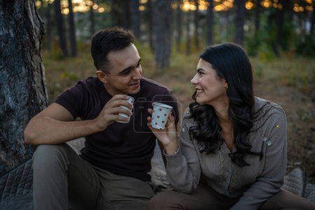 Téléchargez les photos : Jeune couple homme et femme petit ami et petite amie ou mari et femme dans la relation amoureuse tenir tasse de papier de café ou de thé tout en passant du temps ensemble dans la forêt du parc liens amour vraies personnes - en image libre de droit