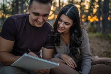 Téléchargez les photos : Homme et femme jeune couple adulte dans la nature tiennent et dessinent dans la nature - en image libre de droit