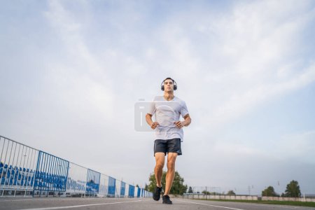 Photo for Adult caucasian man jogging on the running track male athlete in stadium training run in sunny spring or summer day real people healthy lifestyle concept - Royalty Free Image