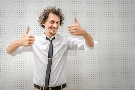 Photo for Portrait of one caucasian adult man stand outdoor wear white shirt happy smile confident copy space stand on front of while wall waist up thumbs up gesture positive emotion success concept - Royalty Free Image