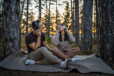 Téléchargez les photos : Homme et femme jeune couple adulte dans la nature écouter de la musique sur écouteurs - en image libre de droit