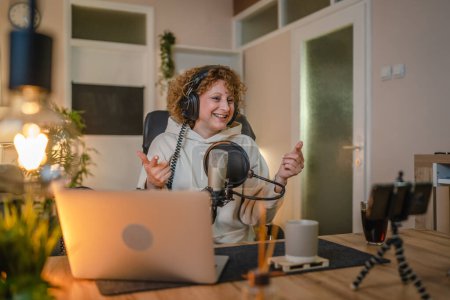 Photo for One woman caucasian female blogger or vlogger gesticulating while streaming video podcast in broadcasting studio use microphone and headphones famous influencer shooting video for channel podcast - Royalty Free Image