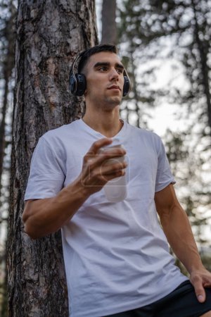 Téléchargez les photos : Un homme caucasien jeune athlète masculin prendre un frein lors de l'entraînement en plein air tenir shaker supplément en main heureux confiant espace de copie forte - en image libre de droit