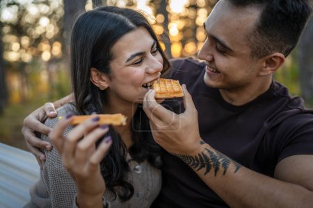 Photo for Couple adult man and woman in love eat waffle in nature park or woods - Royalty Free Image