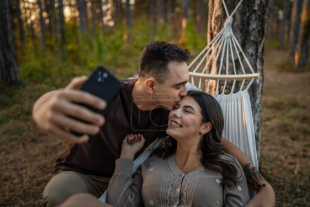 Foto de Hombre y mujer joven pareja adulta en la naturaleza tomar autorretrato foto selfie ugc usar teléfono móvil smartphone o hacer una videollamada - Imagen libre de derechos