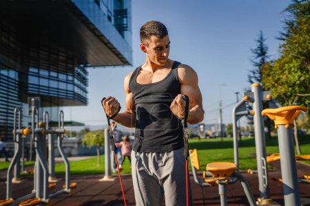 Photo for Adult caucasian man training outdoor in the city day Male athlete using rubber elastic resistance band tubes in his daily workout routine Real people health and fitness concept copy space - Royalty Free Image
