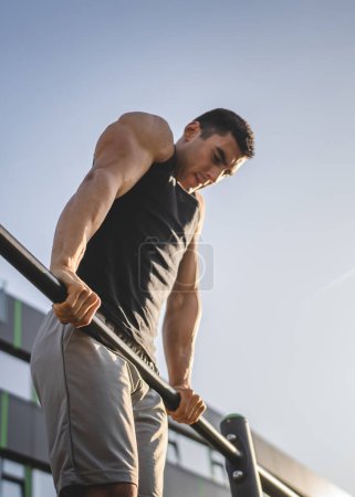 Photo for One man young adult caucasian male athlete training at outdoor open gym pull ups exercise healthy lifestyle and recreation training concept in the city in summer day real people copy space - Royalty Free Image
