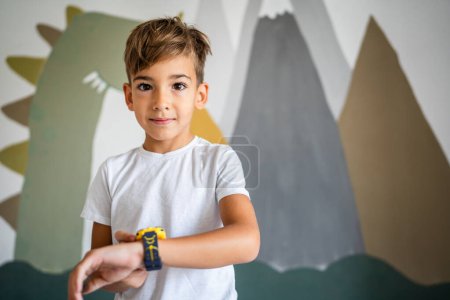 Foto de Niño caucásico 7 años niño varón uso reloj inteligente en casa - Imagen libre de derechos