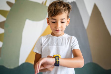 Photo for Caucasian boy 7 years old male child kid use smart watch at home - Royalty Free Image