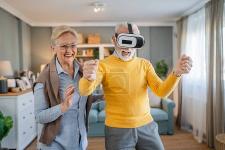 man mature senior caucasian male husband with his wife senior couple at home enjoy virtual reality VR headset