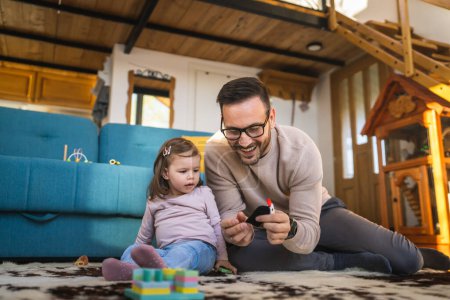 Photo for Father and daughter on the floor at home mature adult caucasian man play with finger puppets with his two years old child toddler girl having fun parenting and bonding family time concept copy space - Royalty Free Image