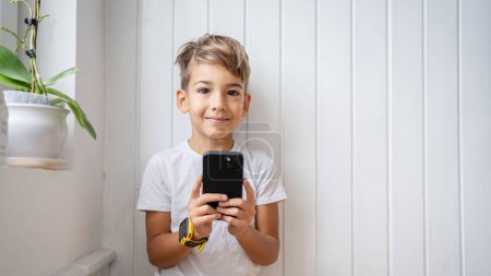 Photo for One small caucasian boy hold mobile phone smartphone take photos - Royalty Free Image