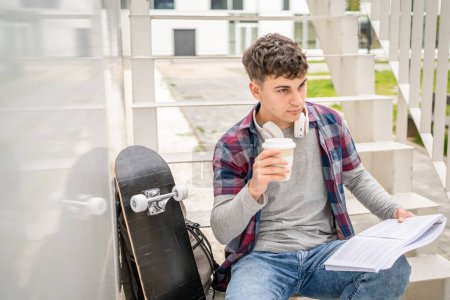 Foto de Un joven adolescente estudiante caucásico con libros leer estudio en el campus en el día sentarse en la escalera concepto de educación espacio de copia - Imagen libre de derechos