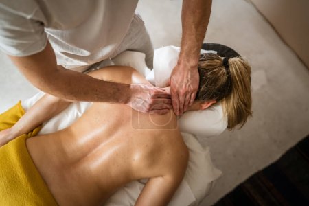 Téléchargez les photos : Femme inconnue allongée tout en ayant massage du cou par le thérapeute caucasien masculin au salon de soins de beauté salon de soins de santé espace de copie concept de relaxation - en image libre de droit