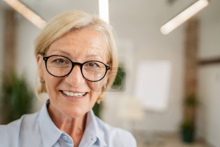 Photo for Portrait of one mature blonde caucasian woman with eyeglasses at home or office happy smile looking to the camera confident copy space - Royalty Free Image