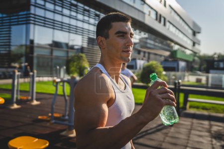 Photo for One man caucasian male athlete hold plastic bottle of water opening and prepare to drink while training outdoor in sunny day hydration and healthy lifestyle concept copy space - Royalty Free Image