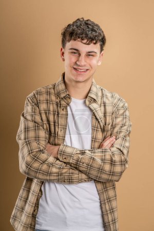 Photo for Portrait of one caucasian man 20 years old looking to the camera in front of almond color studio background smiling wearing casual shirt copy space - Royalty Free Image