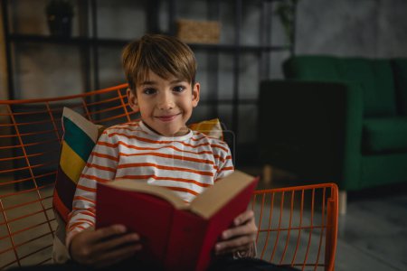 Téléchargez les photos : Un garçon caucasien à la maison a lu un livre dans la vue du soir espace de copie concept d'éducation des personnes réelles - en image libre de droit