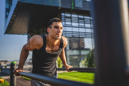 Photo for One man young adult caucasian male athlete training at outdoor open gym dips exercise healthy lifestyle and recreation training concept in the city in summer day real people copy space - Royalty Free Image