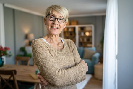 Téléchargez les photos : Portrait rapproché d'une femme âgée aux cheveux courts sourire heureux espace de copie d'émotion positive debout à la maison lunettes de vue de port intérieur - en image libre de droit