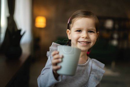 Téléchargez les photos : Un tout-petit fille caucasien enfant tenir un verre de boisson à l'eau à la maison - en image libre de droit