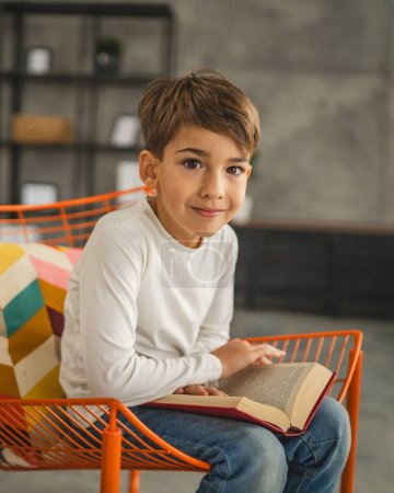 Foto de Un niño caucásico niño de siete años en la habitación en casa leer libro - Imagen libre de derechos