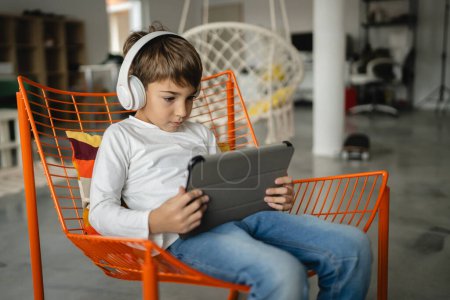 Photo for One schoolboy caucasian boy sit at home use digital tablet - Royalty Free Image