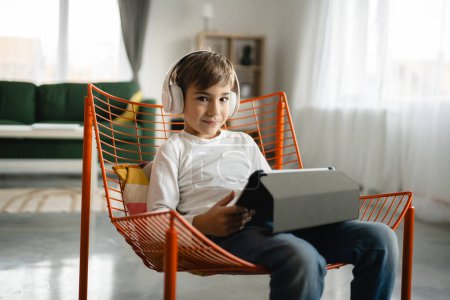 Photo for One schoolboy caucasian boy sit at home use digital tablet - Royalty Free Image