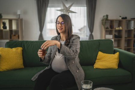 Foto de Mujer embarazada mantenga las pastillas y la prescripción madre embarazada lea el prospecto antes de tomar una medicación tabletas o suplemento - Imagen libre de derechos