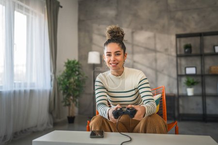 Foto de Una joven mujer caucásica jugar consola de videojuegos usando controlador de joystick mientras está sentado en casa personas reales ocio concepto de espacio de copia - Imagen libre de derechos