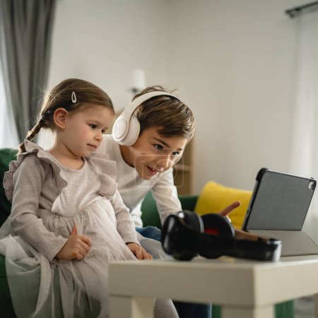 Téléchargez les photos : Frère et sœur petits enfants frères et sœurs utilisent une tablette numérique à la maison regarder la vidéo en ligne - en image libre de droit