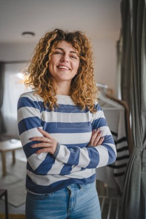 Téléchargez les photos : Portrait de femme caucasienne adulte aux cheveux bouclés à la maison sourire heureux - en image libre de droit