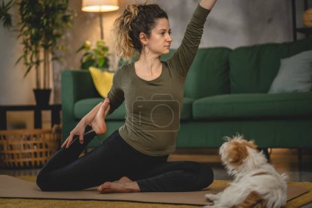 Téléchargez les photos : Femme pratique le yoga sur tapis dans le salon à la maison - en image libre de droit
