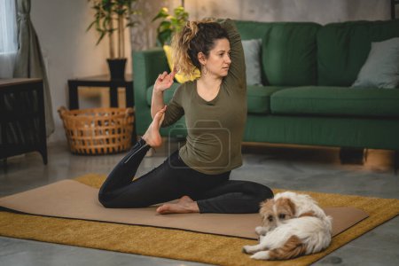Foto de La mujer practica yoga en la estera en la sala de estar en casa - Imagen libre de derechos