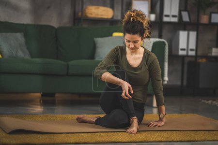 Téléchargez les photos : Femme pratique le yoga sur tapis dans le salon à la maison - en image libre de droit