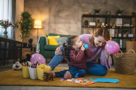 Foto de Madre e hija niña pequeño jugar con globos en azada concepto de vinculación familiar - Imagen libre de derechos