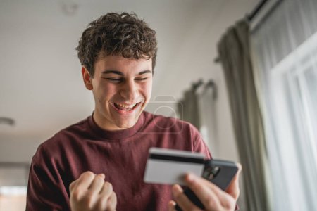 Photo for One teenager young man caucasian male sit at home use credit card shopping online use internet for online purchase active modern e-banking - Royalty Free Image