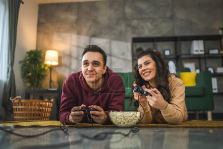 Téléchargez les photos : Couple adulte homme et femme caucasien mari et femme ou petit ami et petite amie jouer à des jeux vidéo de console à la maison maintenez joystick contrôleur avoir plaisir de loisirs joie et de liaison concept - en image libre de droit