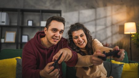 Photo for Adult couple man and woman caucasian husband and wife or boyfriend and girlfriend play console video games at home hold joystick controller have fun leisure joy and bonding concept - Royalty Free Image