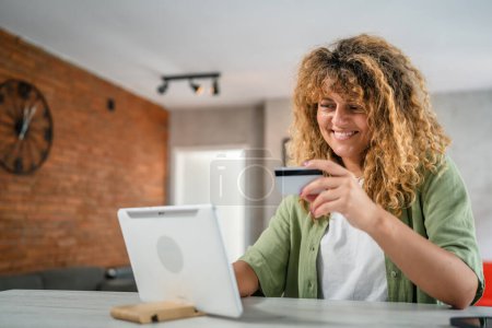 Téléchargez les photos : Une femme adulte à la maison utiliser carte de crédit ou de débit pour les achats en ligne parcourir les magasins en ligne acheter des choses sur la vente à prix réduit personnes réelles copier l'espace utiliser ordinateur portable - en image libre de droit