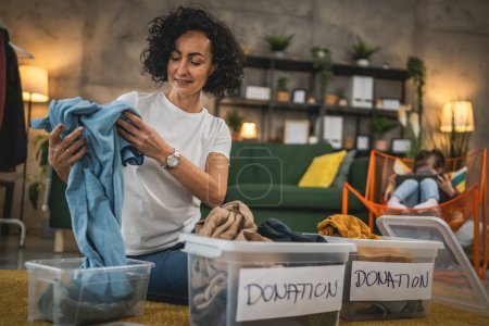 Photo for Adult caucasian woman at home sorting clothes wardrobe for donation - Royalty Free Image