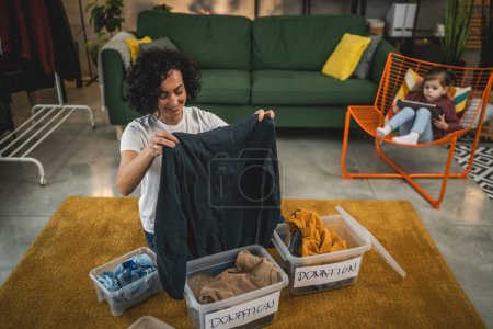 Foto de Mujer caucásica adulta en casa clasificando ropa armario para donación - Imagen libre de derechos