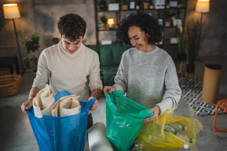 Foto de Madre e hijo mujer y adolescente hombre familia reciclar en casa clasificación de residuos de papel plástico y vidrio a bolsas concepto de vida sostenible - Imagen libre de derechos
