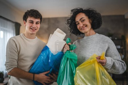 Téléchargez les photos : Mère et fils femme et adolescent homme famille recycler à la maison tri des déchets de papier plastique et de verre aux sacs concept de vie durable - en image libre de droit