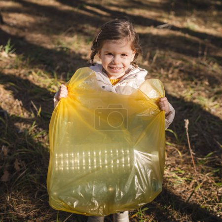 Photo for Girl toddler collect plastic bottle garbage waste in forest - Royalty Free Image