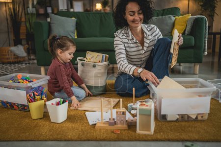 Téléchargez les photos : Mère et fille tout-petit à la maison collecter des jouets mis en boîte salle blanche - en image libre de droit