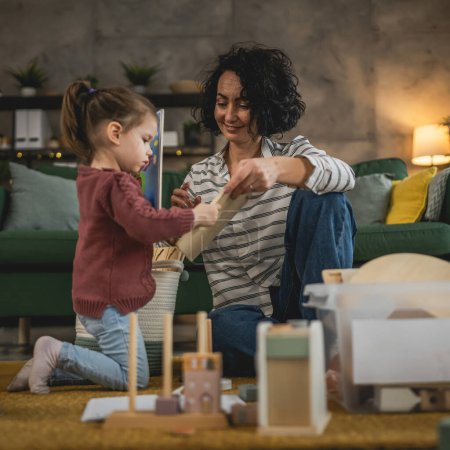 Téléchargez les photos : Mère et fille tout-petit à la maison collecter des jouets mis en boîte salle blanche - en image libre de droit