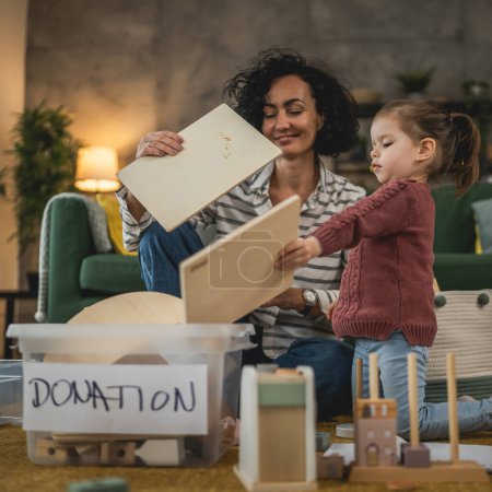 Téléchargez les photos : Mère et fille tout-petit à la maison choisissent des jouets pour le don de charité - en image libre de droit